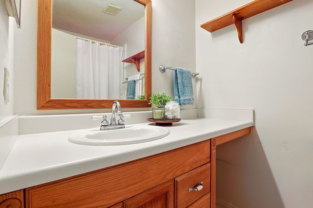 bathroom featuring visible vents, a textured ceiling, and vanity