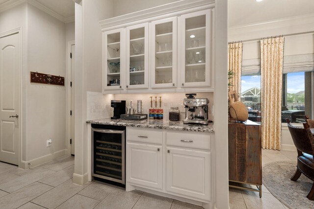 bar featuring ornamental molding, decorative backsplash, wine cooler, light tile patterned flooring, and baseboards