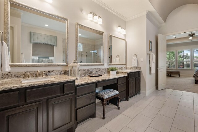 full bath with crown molding, a ceiling fan, double vanity, tiled shower, and a sink