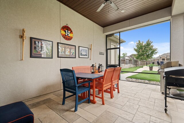 dining space with wooden ceiling, a textured wall, a ceiling fan, and stone tile floors