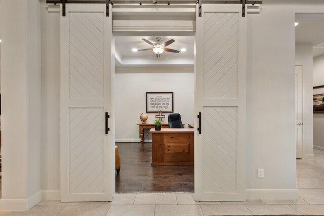 interior space featuring baseboards, a ceiling fan, and a barn door