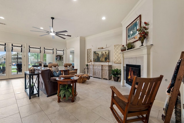 living area with ornamental molding, french doors, recessed lighting, a tiled fireplace, and a ceiling fan