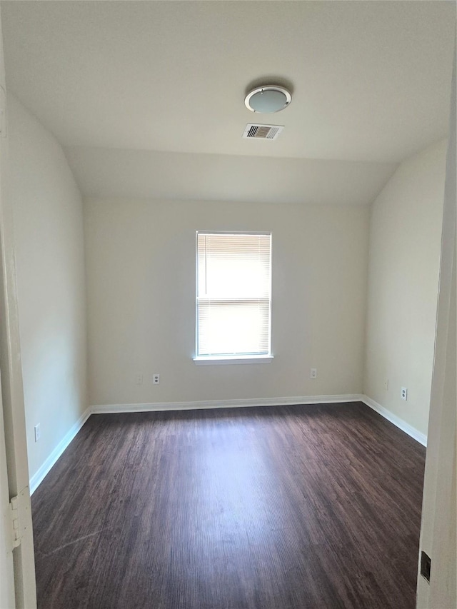 unfurnished room featuring baseboards, vaulted ceiling, dark wood-style floors, and visible vents