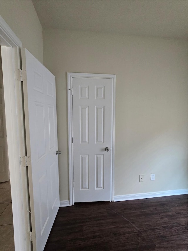 unfurnished bedroom with baseboards and dark wood-style floors