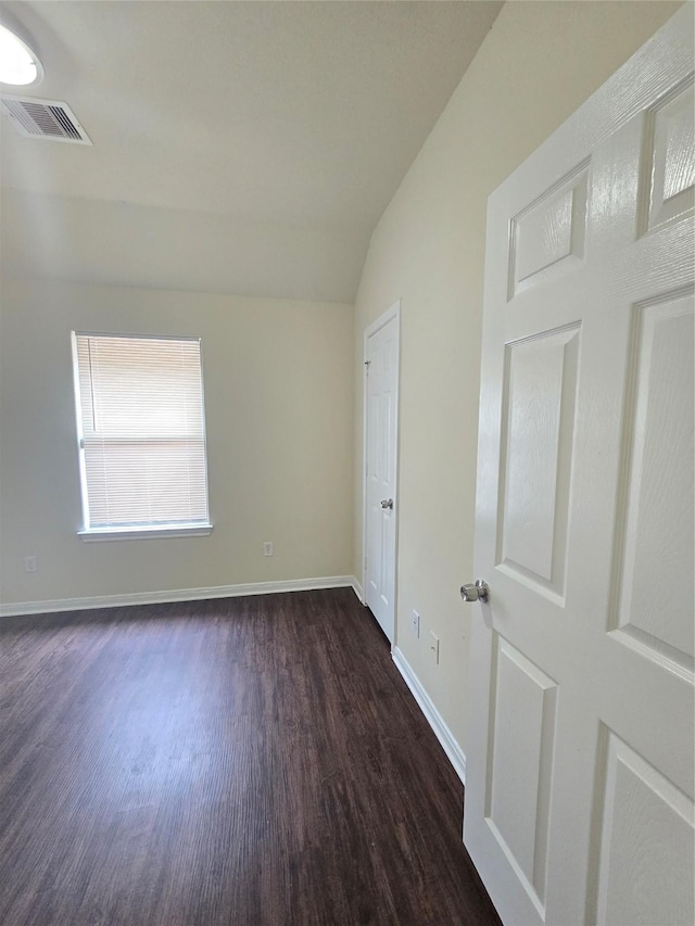 interior space featuring baseboards, visible vents, lofted ceiling, and dark wood-type flooring