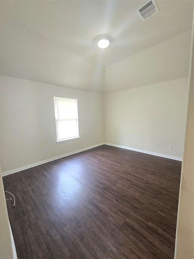 unfurnished room featuring baseboards, visible vents, lofted ceiling, and dark wood-type flooring