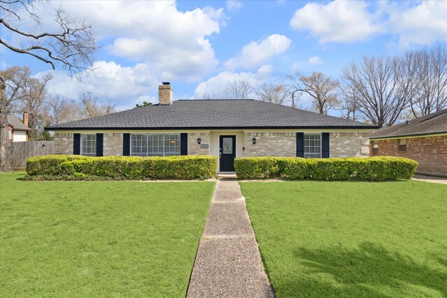 ranch-style home with brick siding, fence, a chimney, and a front yard