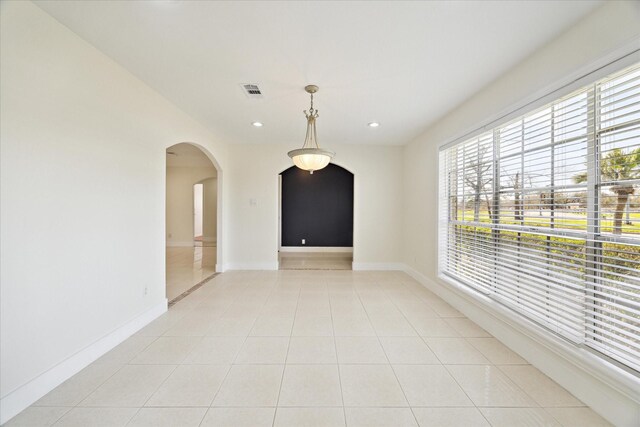 unfurnished room with plenty of natural light, recessed lighting, arched walkways, and light tile patterned flooring