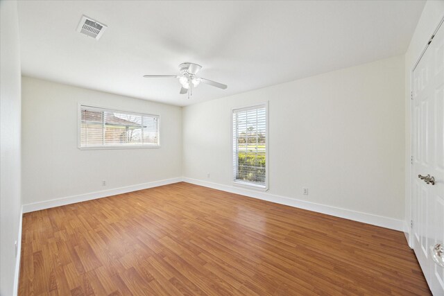 empty room featuring a wealth of natural light, light wood-type flooring, and visible vents