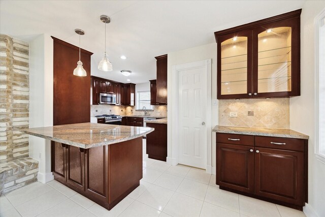 kitchen with decorative backsplash, a peninsula, glass insert cabinets, a sink, and stainless steel appliances