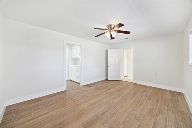 empty room featuring a ceiling fan, baseboards, visible vents, and light wood-type flooring