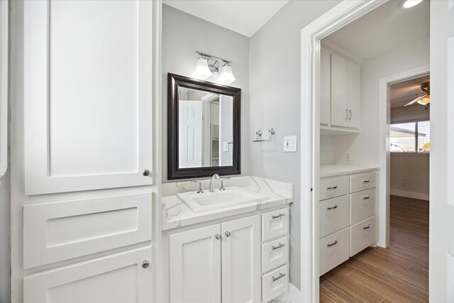 bathroom with ceiling fan, vanity, baseboards, and wood finished floors