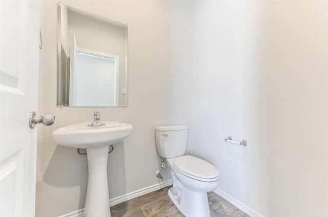 16524 Cascading Pines Ct, Conroe, TX 77302 - half bathroom featuring baseboards, toilet, and wood finished floors