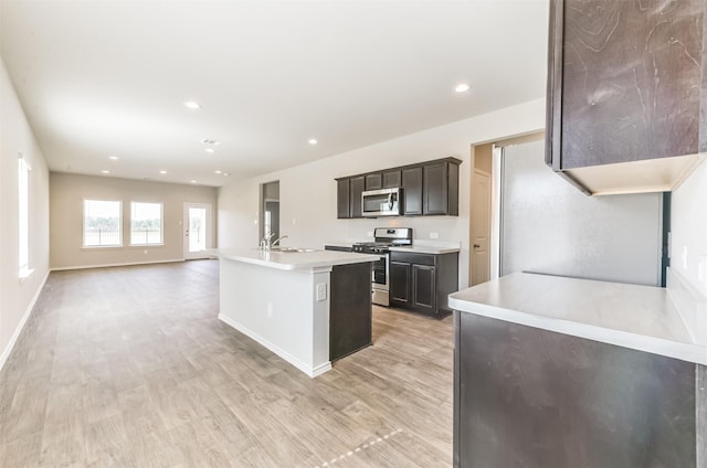 16524 Cascading Pines Ct, Conroe, TX 77302 - kitchen with appliances with stainless steel finishes, a sink, light wood finished floors, light countertops, and a kitchen island with sink