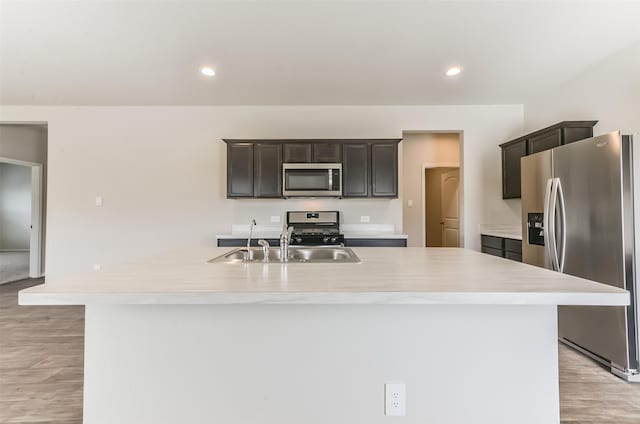 16524 Cascading Pines Ct, Conroe, TX 77302 - kitchen featuring a center island with sink, light countertops, a sink, light wood-style flooring, and appliances with stainless steel finishes
