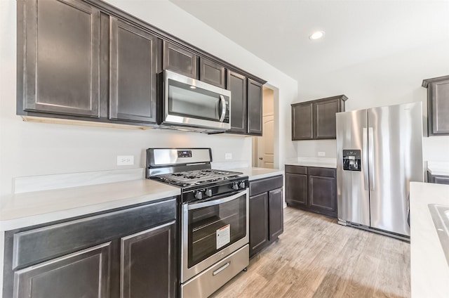 16524 Cascading Pines Ct, Conroe, TX 77302 - kitchen with light countertops, stainless steel appliances, dark brown cabinetry, and light wood-type flooring