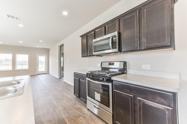 16524 Cascading Pines Ct, Conroe, TX 77302 - kitchen with dark brown cabinetry, visible vents, a sink, light countertops, and stainless steel appliances