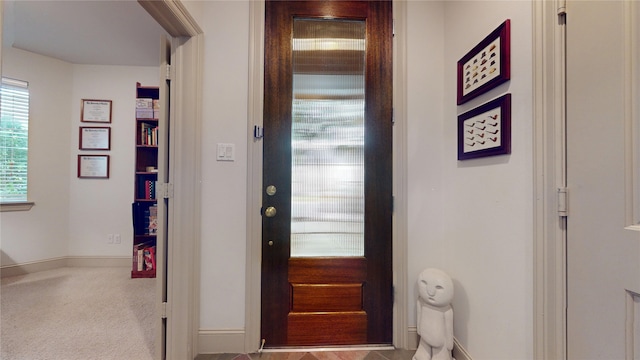 entryway with baseboards and carpet