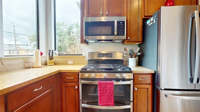 kitchen featuring light countertops, appliances with stainless steel finishes, and brown cabinetry