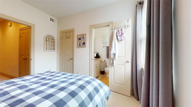 bedroom featuring light carpet, ensuite bath, and visible vents