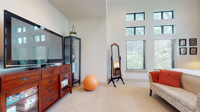 sitting room with baseboards, light carpet, and a towering ceiling