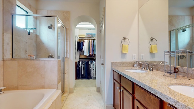 bathroom featuring a spacious closet, a shower stall, and a sink