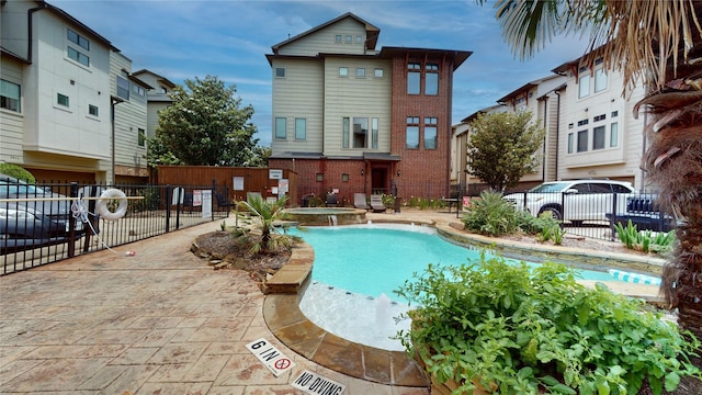 view of pool with a patio, fence, and a pool with connected hot tub