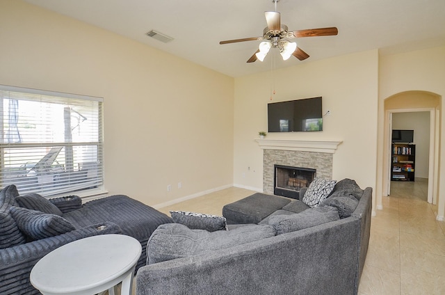 18235 Bonham Oaks Ct, Richmond, TX 77407 - living area with a fireplace, arched walkways, a ceiling fan, light tile patterned floors, and visible vents