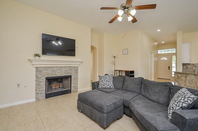 18235 Bonham Oaks Ct, Richmond, TX 77407 - living area featuring a ceiling fan, a stone fireplace, arched walkways, baseboards, and light tile patterned flooring