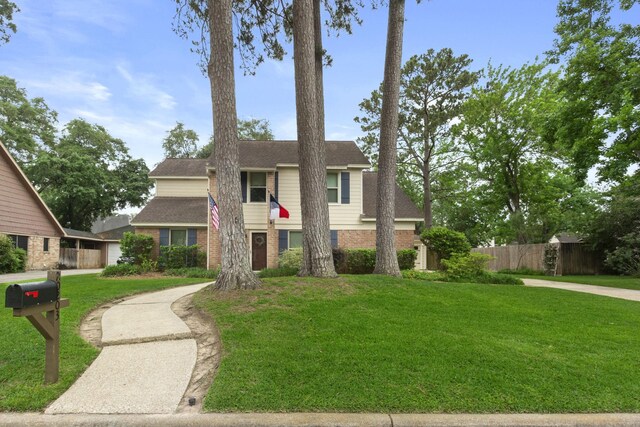 view of front of home with fence, a shingled roof, a front lawn, and brick siding