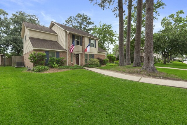 traditional-style home featuring fence, roof with shingles, a front lawn, and brick siding