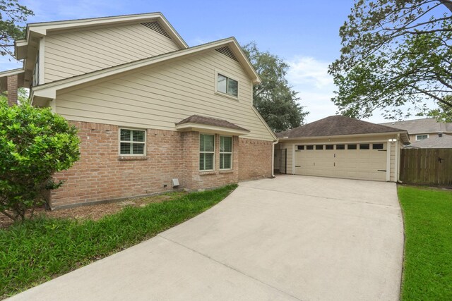 view of side of home featuring brick siding, fence, and a garage