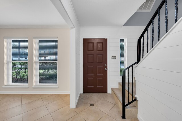entrance foyer with visible vents, stairway, baseboards, ornamental molding, and light tile patterned flooring