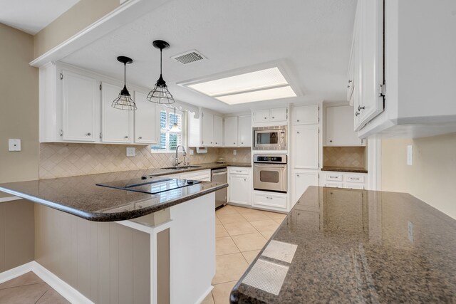 kitchen with visible vents, a peninsula, light tile patterned flooring, a sink, and appliances with stainless steel finishes