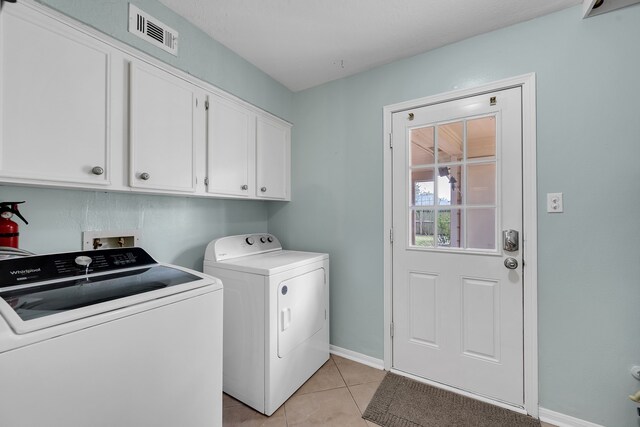 laundry room with visible vents, light tile patterned flooring, baseboards, washer and clothes dryer, and cabinet space