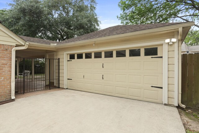garage with concrete driveway, fence, and a gate