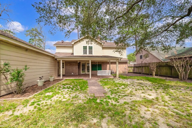 back of property with french doors, a shingled roof, fence private yard, and brick siding