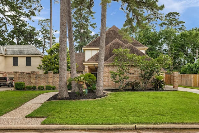 view of front of property featuring brick siding, a front lawn, and fence
