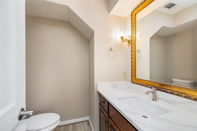 half bathroom with toilet, baseboards, visible vents, and vanity