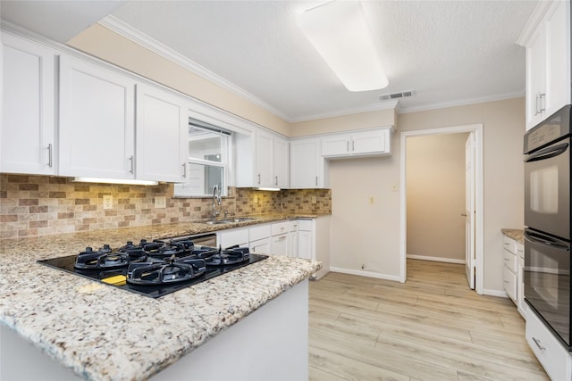 kitchen with visible vents, a sink, white cabinetry, and black appliances
