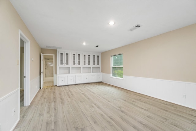 interior space with light wood-type flooring, recessed lighting, wainscoting, and visible vents