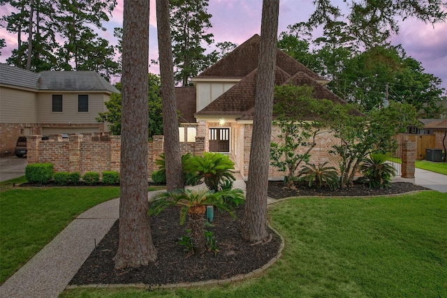 view of front facade with a lawn, central AC, and fence