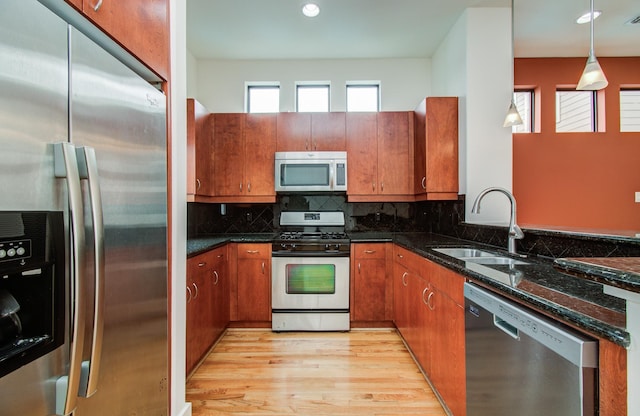 402 Parker St, Houston, TX 77007 - kitchen featuring brown cabinetry, dark stone counters, a sink, light wood finished floors, and stainless steel appliances