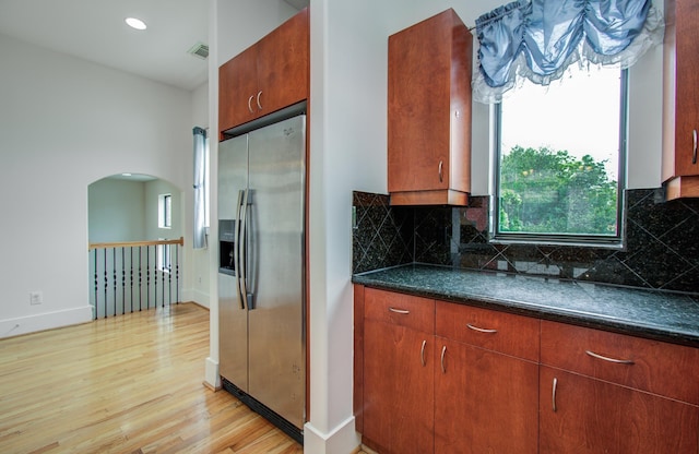 402 Parker St, Houston, TX 77007 - kitchen featuring stainless steel fridge with ice dispenser, arched walkways, light wood-style flooring, decorative backsplash, and visible vents
