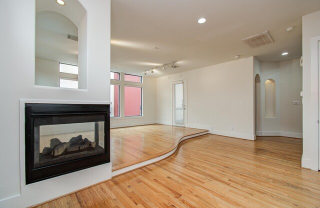 402 Parker St, Houston, TX 77007 - unfurnished living room featuring visible vents, arched walkways, baseboards, and wood finished floors