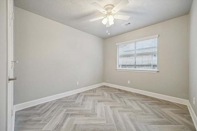 empty room with baseboards, a ceiling fan, a textured ceiling, and visible vents