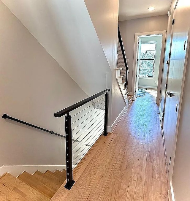 hall with stairway, baseboards, and light wood finished floors