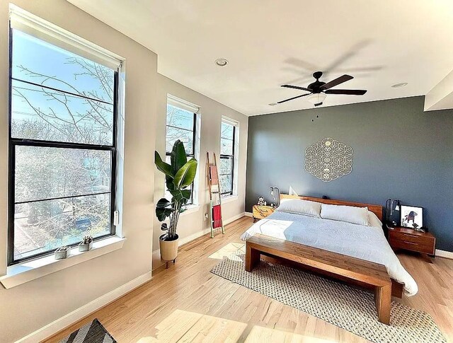bedroom featuring baseboards, light wood-style floors, and ceiling fan