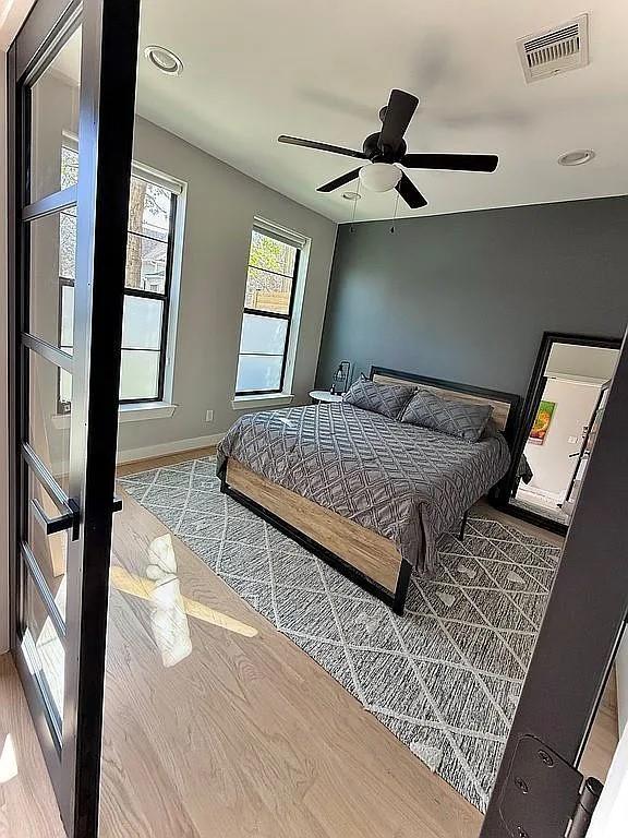 bedroom with a ceiling fan, baseboards, visible vents, and wood finished floors