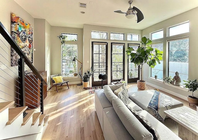 interior space featuring visible vents, a ceiling fan, light wood-style floors, and stairs